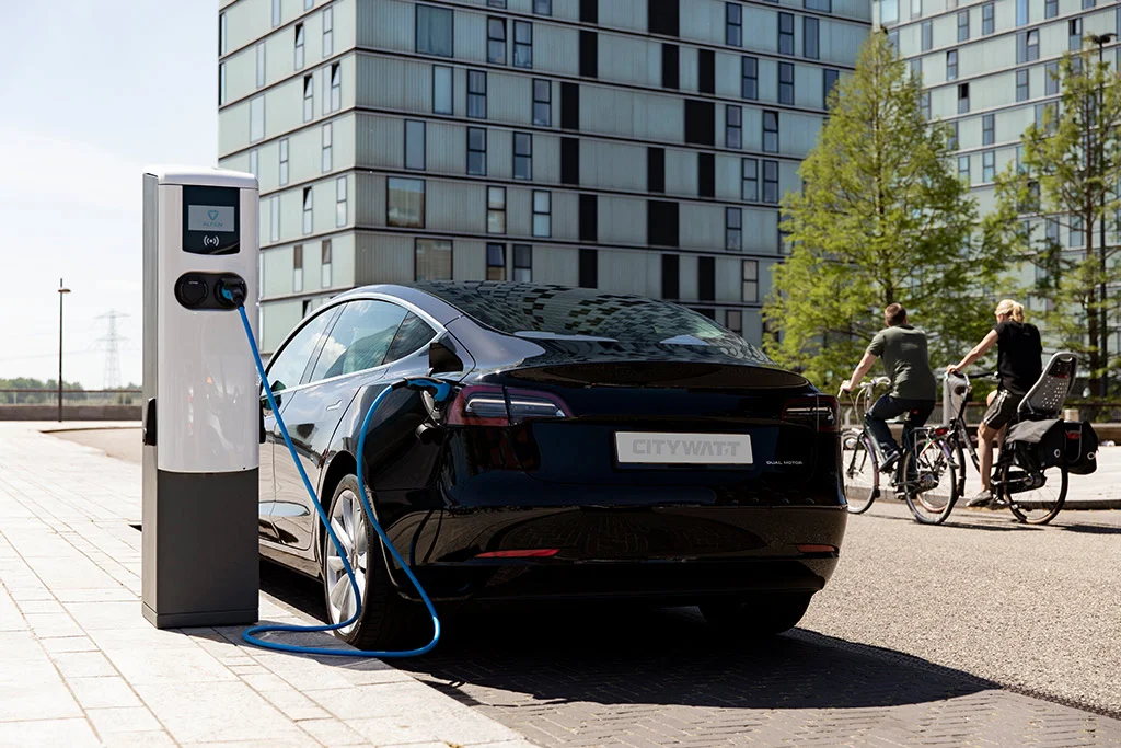 Elektroauto an Ladesäule vor modernem Wohn- und Geschäftsgebäude